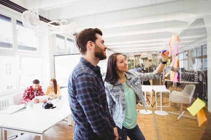 Photo of young man and woman working on whiteboard